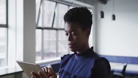 Mixed-race-businesswoman-standing-using-digital-tablet-in-office