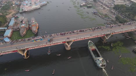 a cargo ship passing under buriganga river bridge - aerial top down drone flight shot