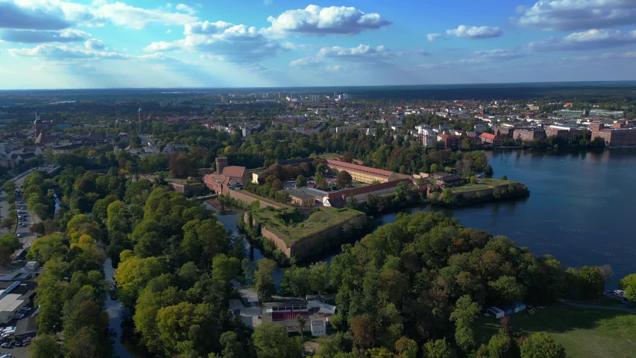 Spandau Citadel, en imponerende renæssancefæstning omgivet af vand, står under en klar himmel. Flot drone panoramaflyvning med overblik.