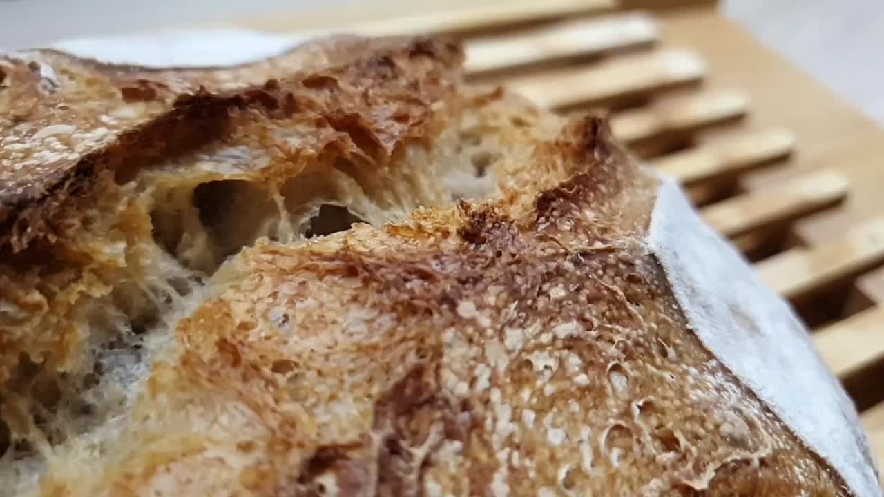 Homemade sourdough crusty bread. Review of a fresh loaf of bread. Closeup of delicious and crunchy bread crust.  Beautifully golden baked bread made with sourdough on wooden table.