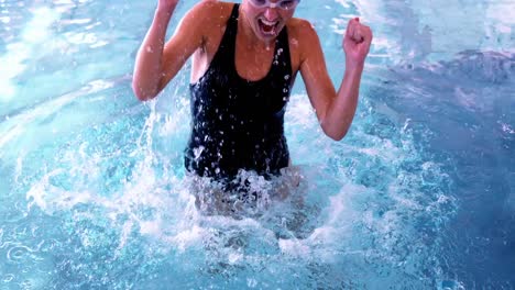 fit swimmer jumping up and cheering in the pool