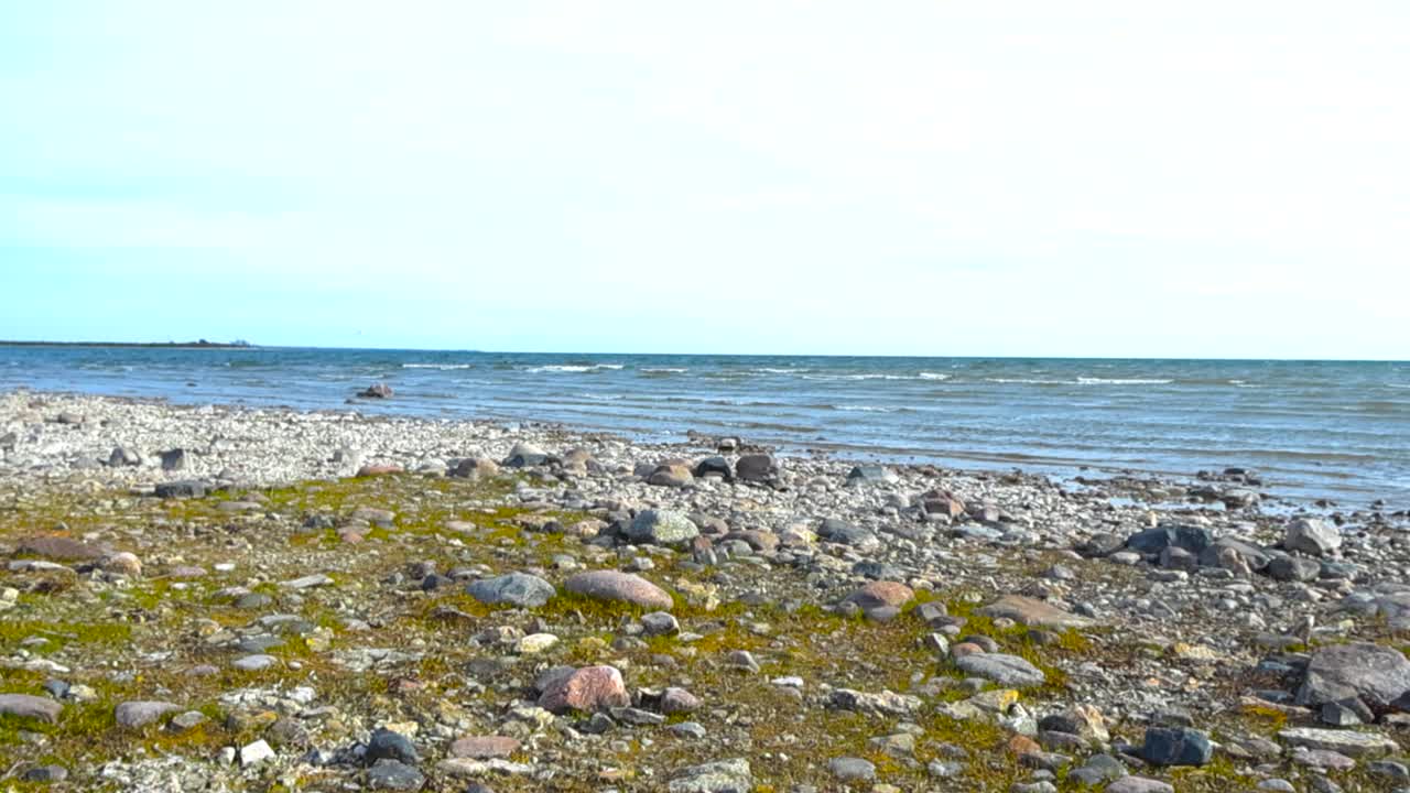 Serene view from a pebble-stone shore overlooking the blue coastal sea at Puhtu, Estonia. Rugged rocky beach and gentle rolling waves, natural beauty of Baltic coastal landscape with beach stones