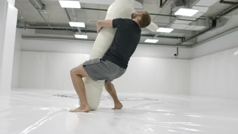 a strong mma fighter is training to throw a scarecrow. testing wrestling equipment.