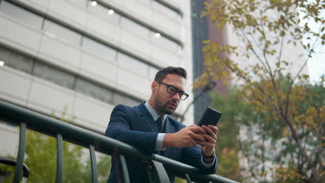 upset businessman reacting while reading bad news on his cell phone