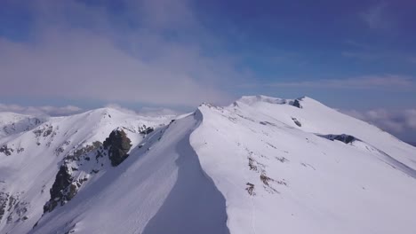 Cielo-Azul-Brillante-Y-Nubes-Suaves-Sobre-Picos-Montañosos-Cubiertos-De-Nieve