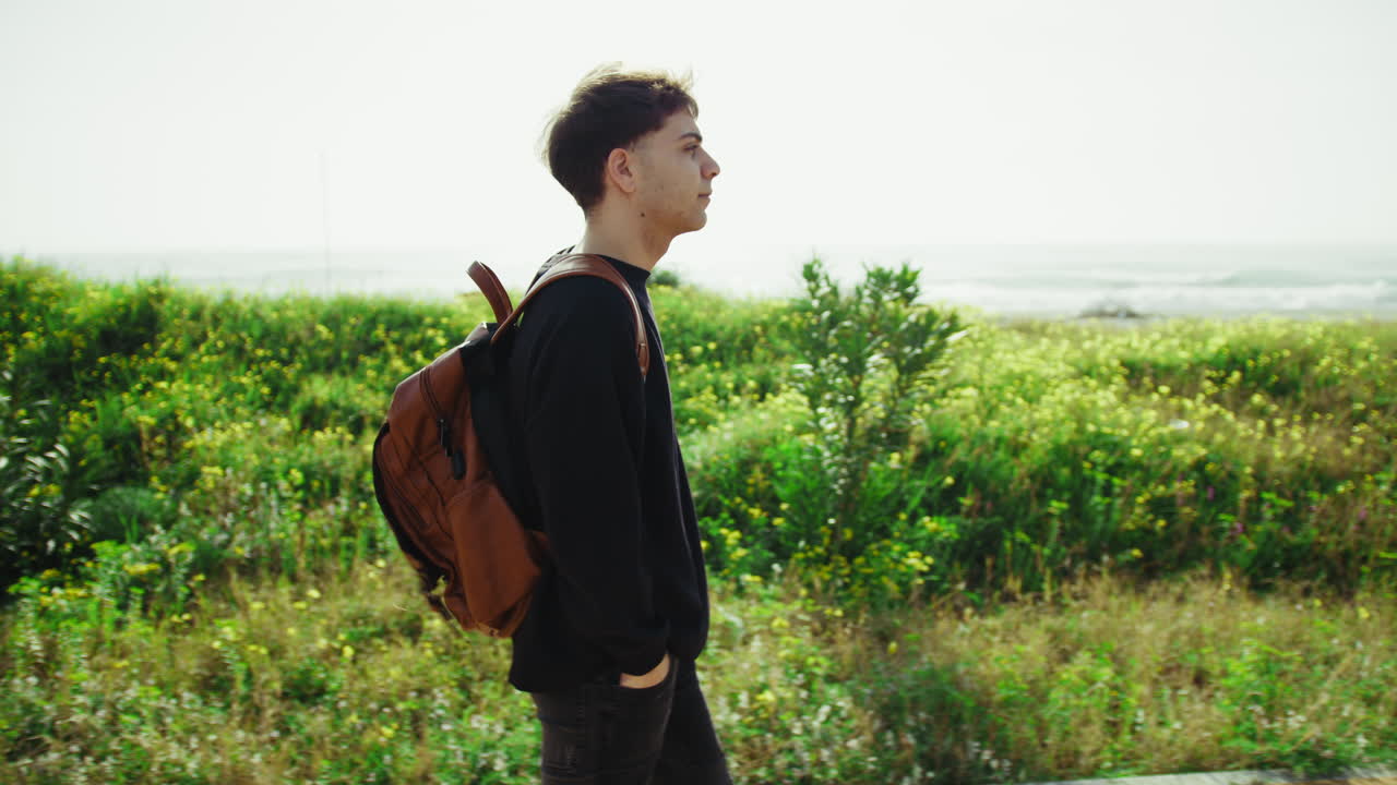 Man With Backpack Taking A Walk In The Nature Near The Grass
