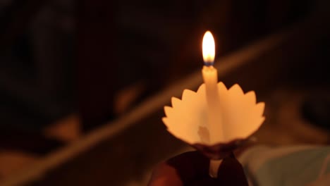 small burning candle with steady flame in a dark room