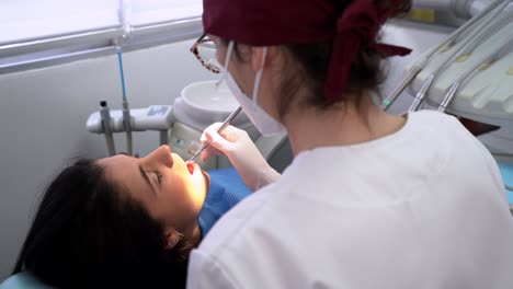 Crop-dentist-curing-tooth-of-female-patient