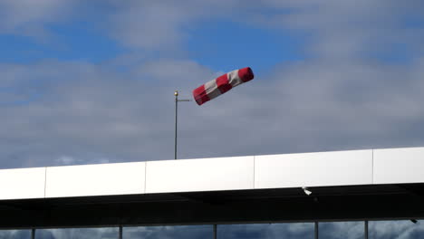 Una-Manga-De-Viento-Aislada-En-Un-Aeródromo-Con-Fuertes-Vientos-Con-Un-Telón-De-Fondo-De-Nubes-Blancas-Y-Cielo-Azul