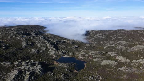 Luftaufnahme-Eines-Wunderschönen-Sees-Oben-In-Den-Bergen,-Umgeben-Von-Wolken