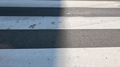 shadow of person crossing pedestrian zebra lines