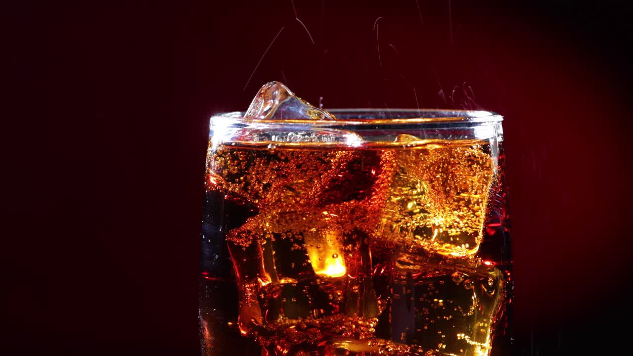 con hielo y burbujas de cola en vaso.