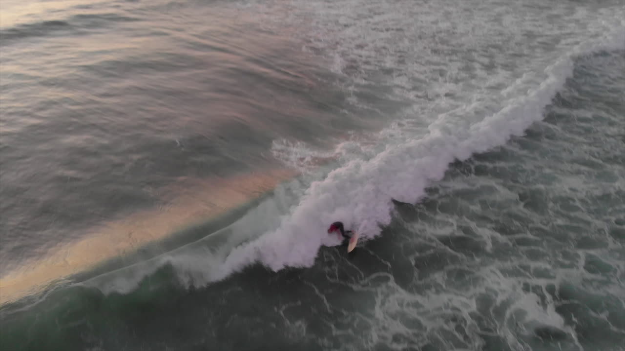 Surfista che cavalca le onde perfette in Algarve, Portogallo, al tramonto. - Ripresa aerea con drone.