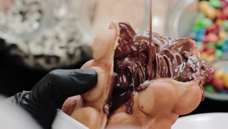 pouring melted chocolate on a waffle in a candy store