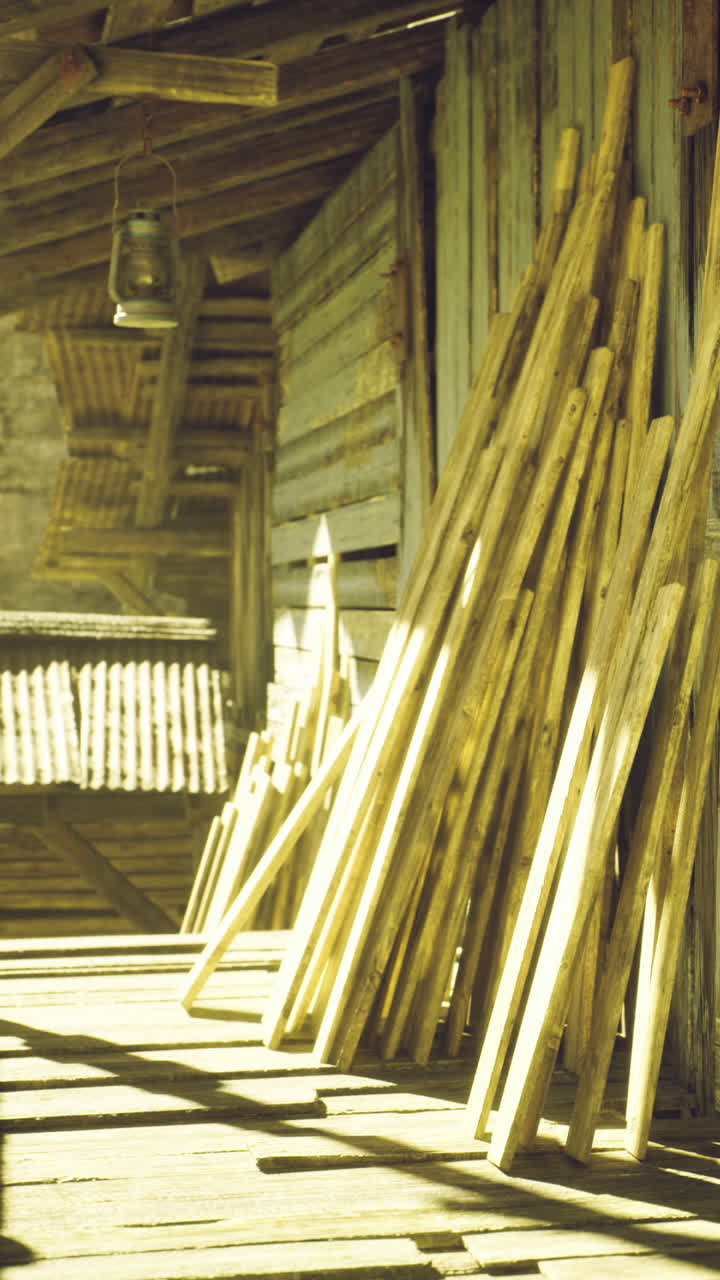 Sunlight bathes rustic wooden sticks on a weathered porch at an old barn