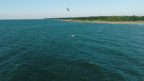 establishing aerial view of a group of people engaged in kitesurfing, sunny summer day, high waves, extreme sport, baltic sea karosta beach , birdseye drone dolly shot moving right