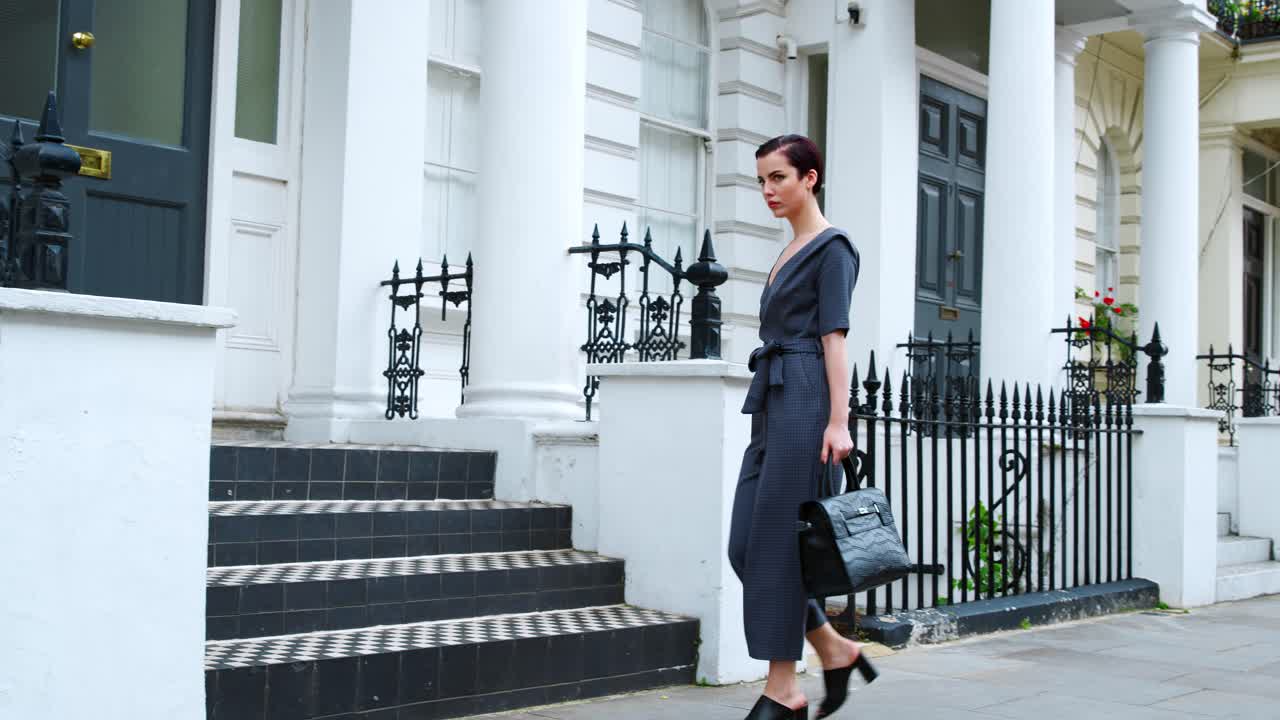 스타일리시한 여자 가방을 들고 도시 거리를  ⁇ 고 있습니다.