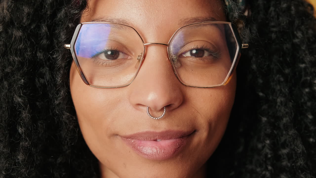 Nahaufnahme-Porträt einer lächelnden Frau mit Brille und lockigem Haar