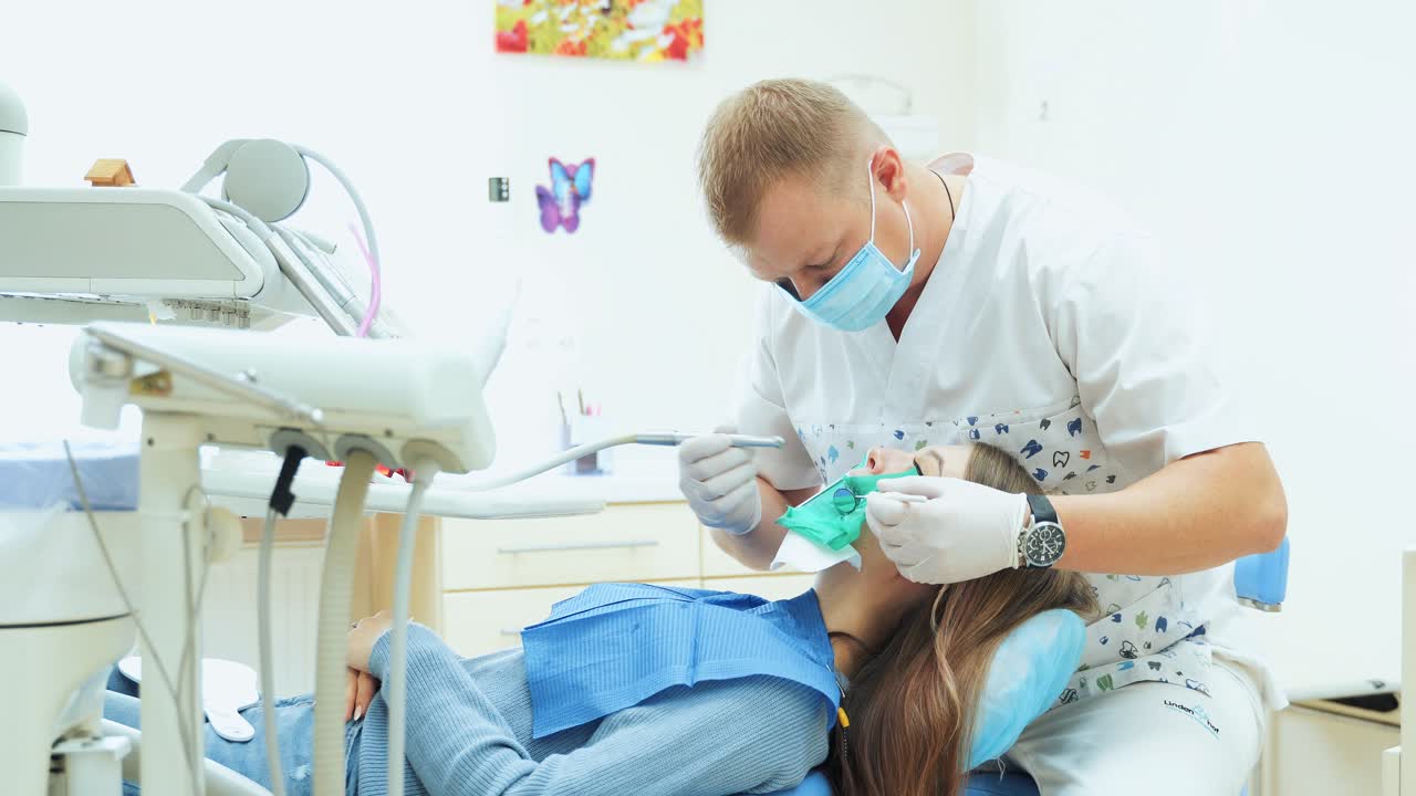 A male dentist treats a tooth with a drill to a patient. Reception at the dental office