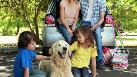 family with dog next to car