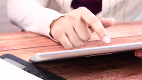 person using a tablet on a wooden table