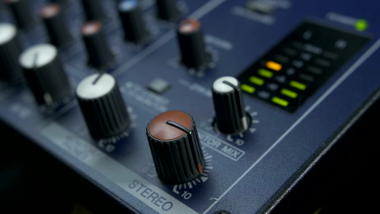 Male fingers turning fader knob on audio mixer