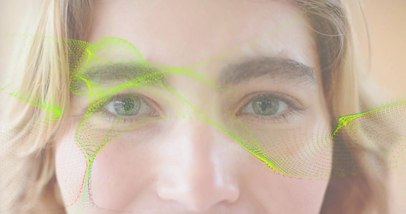 Femme adulte regardant une vague verte commencer à scanner son visage, clignant des yeux, reculant et souriant pour une démo technologique