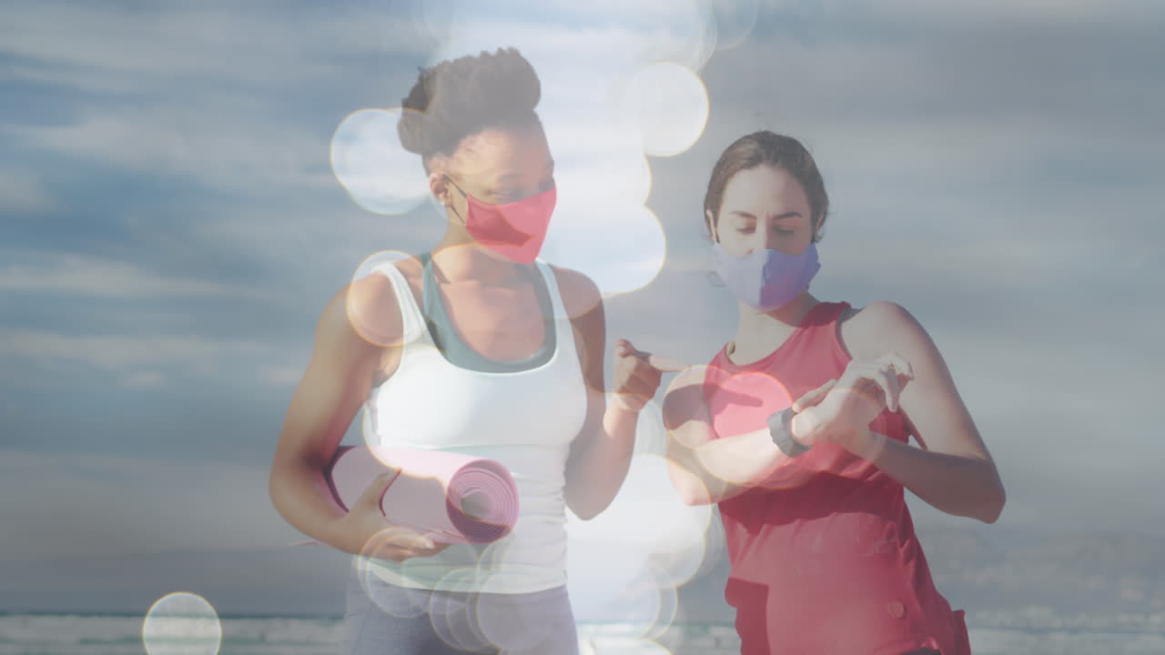 animación de puntos de luz sobre diversas amigas con esteras de yoga y máscaras faciales en la playa