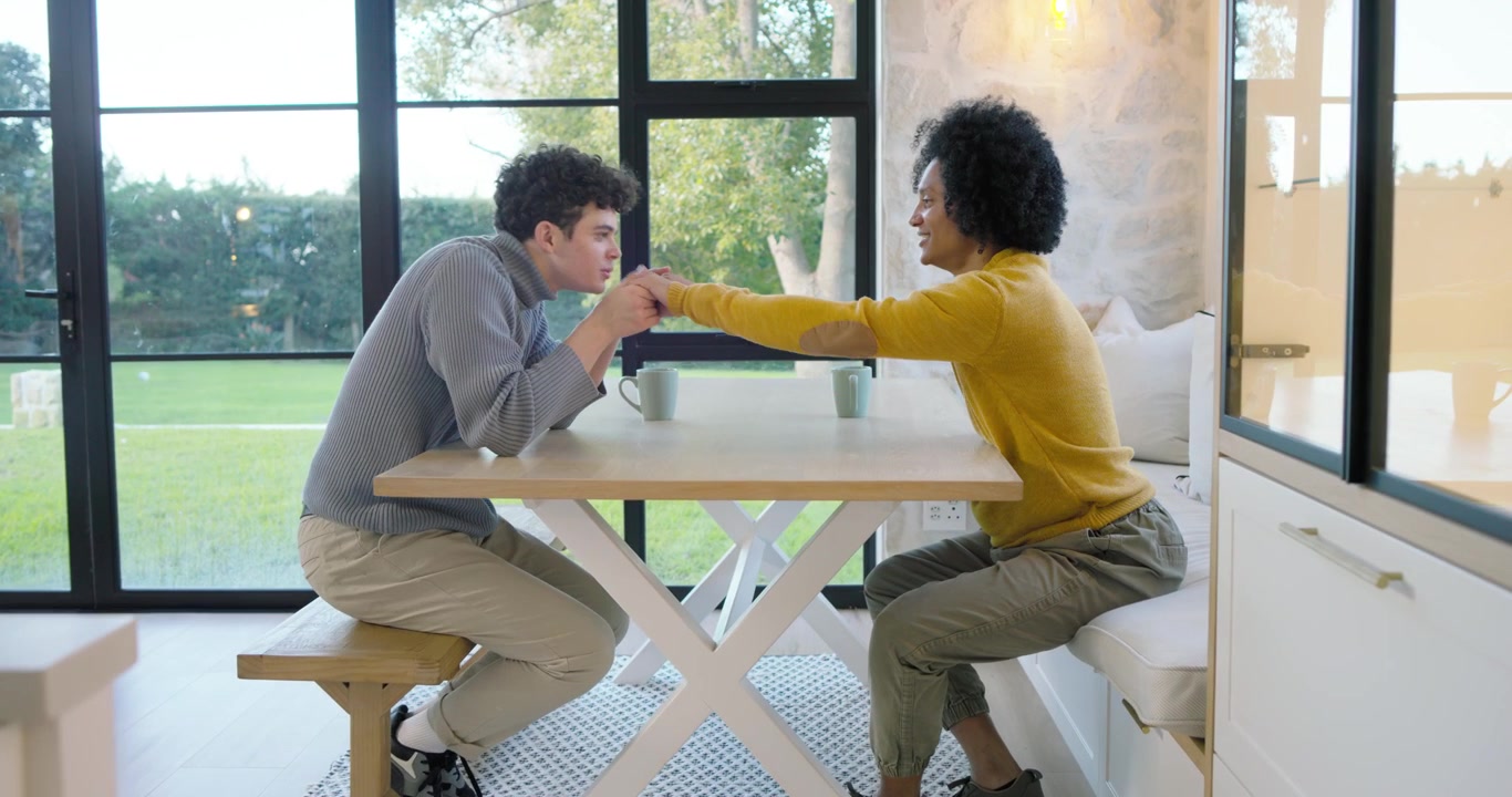 Young Couple Holding Hands and Talking at Home
