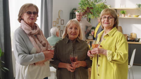 retrato de mujeres mayores felices con bebidas en una fiesta en casa