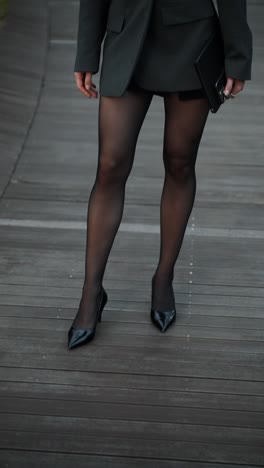 a fashionable caucasian businesswoman holding a phone and tablet looks at the camera on a seoul rooftop, her strong, pretty face revealed in a slow tilt-up and push-in shot