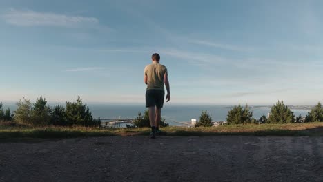 Male-Man-Looks-Out-Over-Sea-and-City-After-Exercise