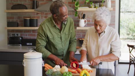 senior african american husband and mixed race wife cooking together at home