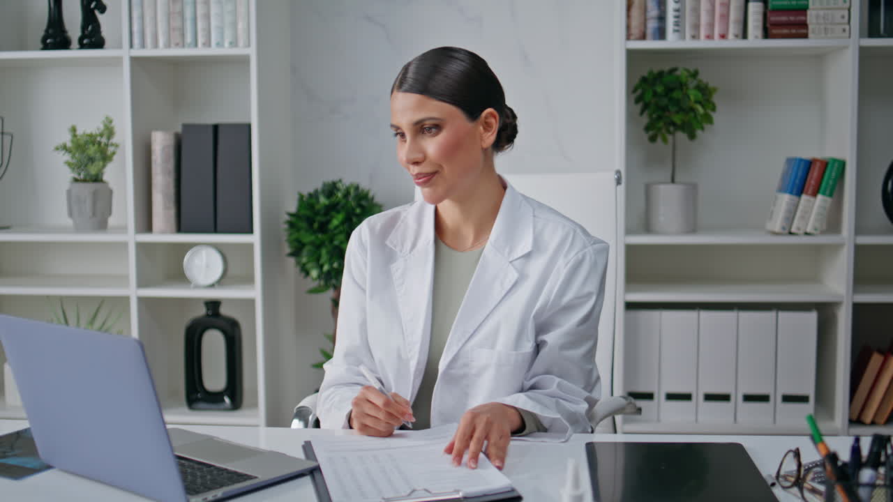 Remote doctor filling form talking at online consultation in polyclinic closeup