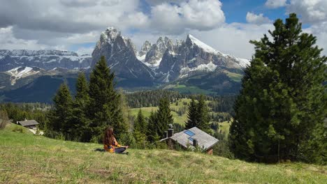 a video of a girl meditating in alpi di siusi, italian dolomites, with snow-capped peaks and a serene mountain valley