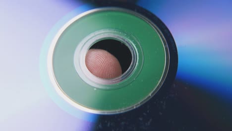 compact disk on person finger on blurred dark background