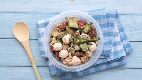 healthy avocado salad with mozzarella, sun-dried tomatoes, walnuts and cucumber