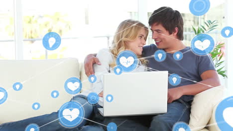 Animation-of-network-of-connections-with-icons-over-caucasian-couple-using-laptop