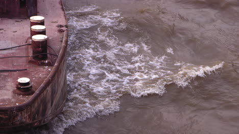 Slow-motion-footage-of-the-front-of-ship-that-is-moving-upstream-on-the-Seine-river-with-waves-bouncing-off-the-hull