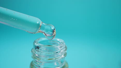 closeup of a dropper bottle with a drop of clear liquid falling into it