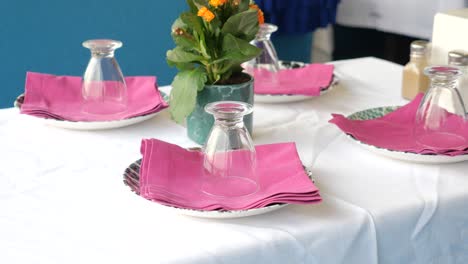 a restaurant table setting with pink napkins