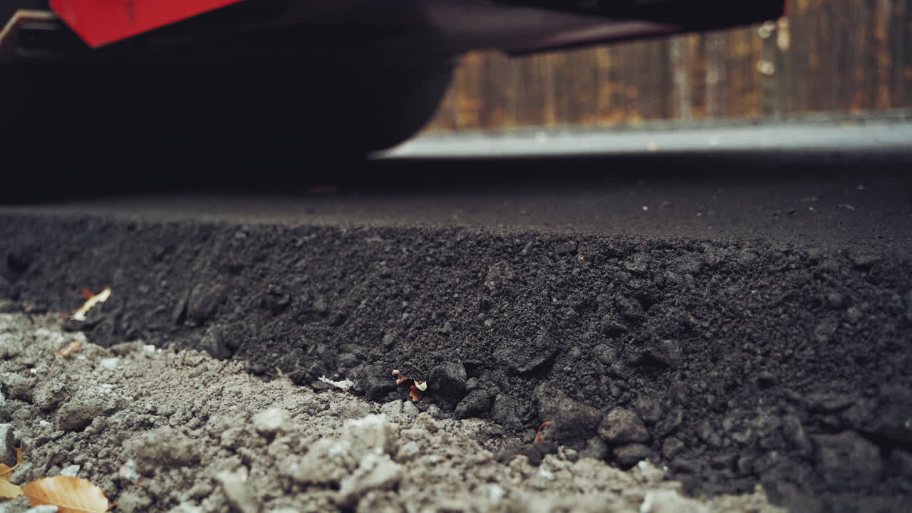 Close-up of a big black asphalt roller machine pressing a new bitumen. Compactor machine stucking hot asphalt with heavy vibrator doing new road.