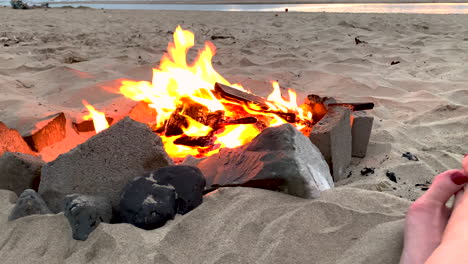 slow motion parallax of beach campfire, revealing feet of woman enjoying evening