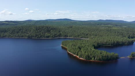 Drone-shot-of-crystal-clear-lake-in-Sweden-inland-surrounded-by-deep-forest-landscape