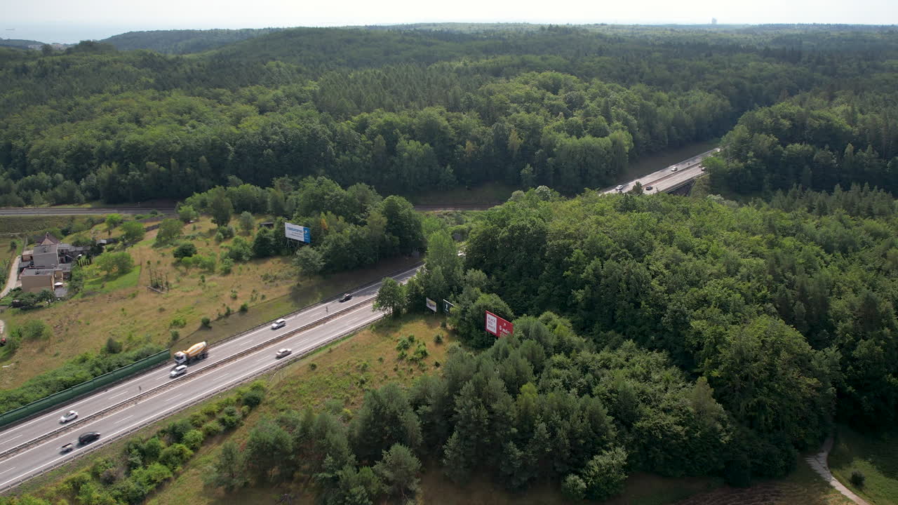 carretera asfaltada con tráfico diurno a través del paisaje boscoso en gdynia, polonia
