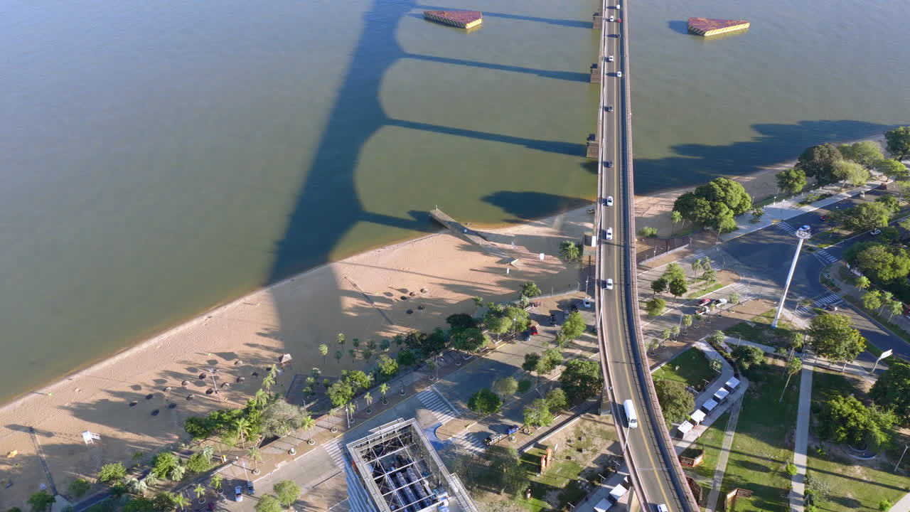 Aerial drone shot of traffic on a major bridge spanning the Paraná River with Corrientes cityscape and surrounding developments visible