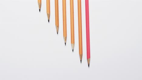 Overhead-view-of-pencils-arranged-on-white-background,-in-slow-motion
