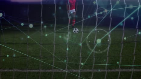 Animation-of-network-of-connections-over-mid-section-of-male-soccer-player-taking-a-penalty-kick