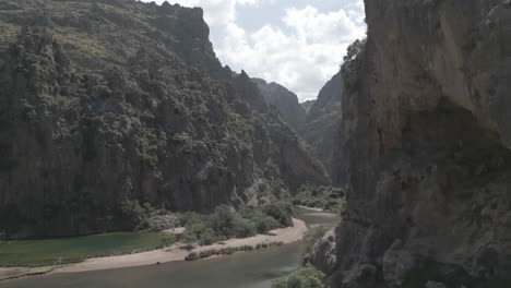 breathtaking 4k drone footage gliding between two towering cliffs at sa calobra, mallorca. this cinematic flythrough captures the dramatic rock formations, narrow canyon.