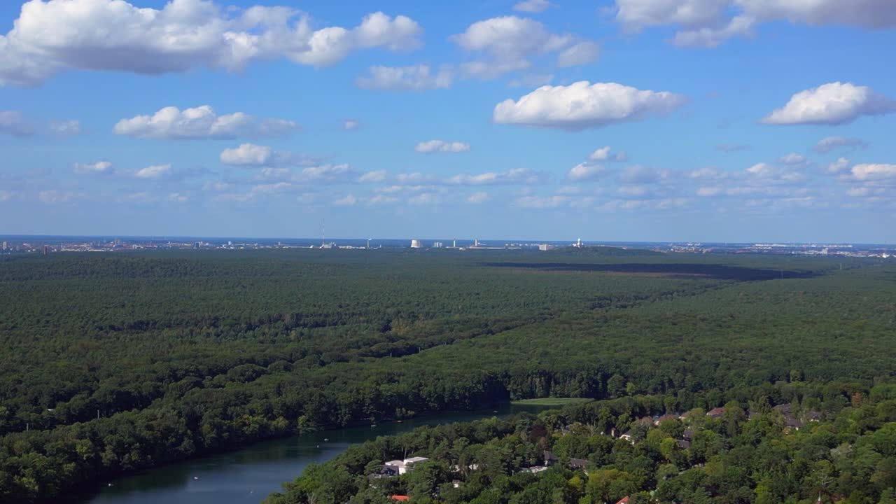 푸른 하늘과 구름을 가진 은 날, 울창한 푸른 숲에 둘러싸인 호수를 볼 수 있습니다.